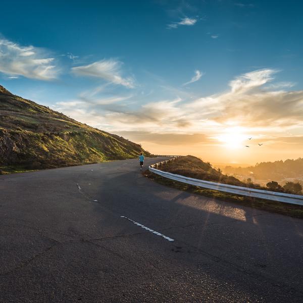 Person running on mountain road at dusk.