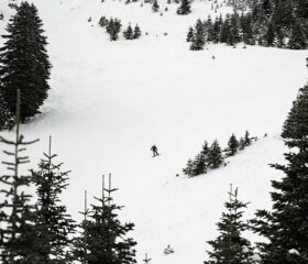 Person snowboarding down snow covered ski slope.
